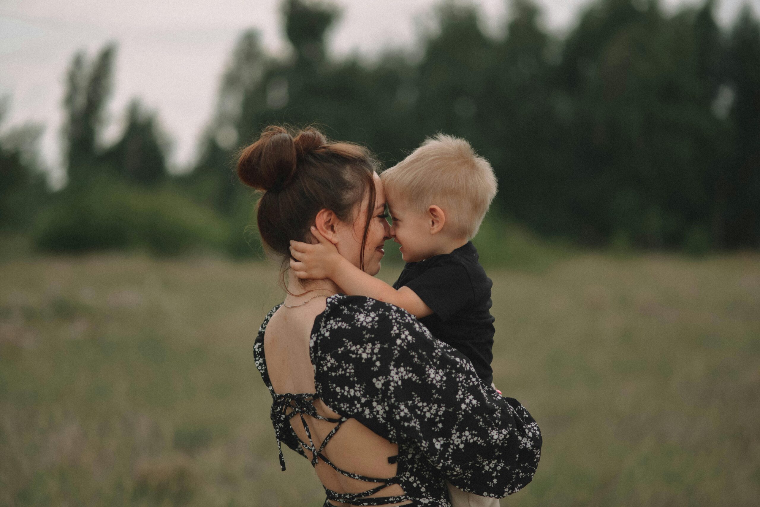 A touching moment between a mother and her child in a serene outdoor setting.